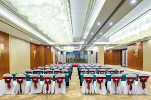 A conference room with rows of chairs, a red carpet, and a cityscape mural on the wall.