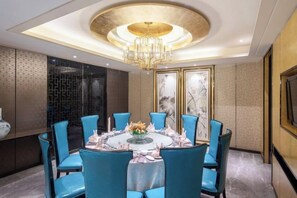 A dining room with a round table, blue chairs, and a chandelier.