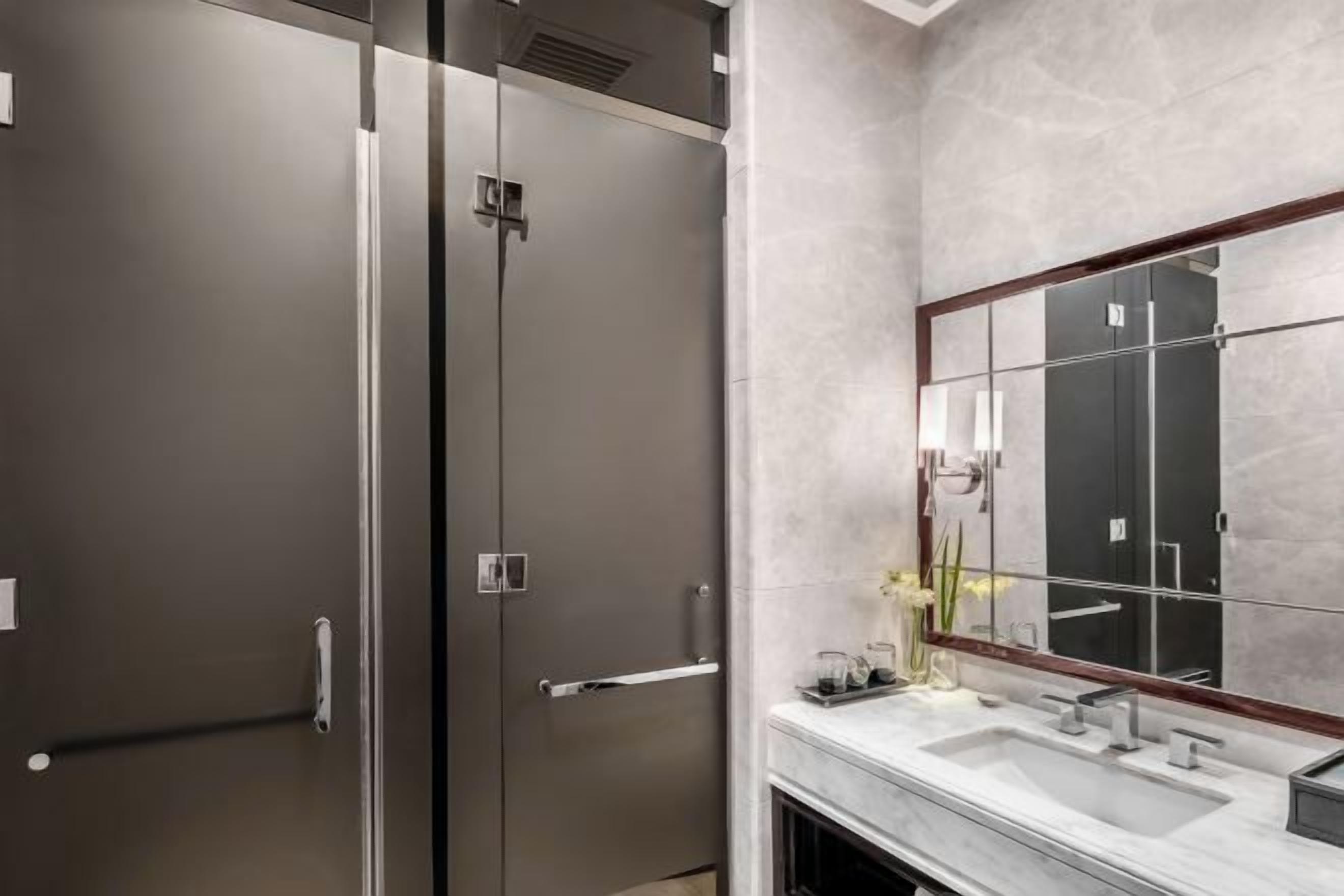 A modern bathroom with a large mirror, a sink, and a shower area.