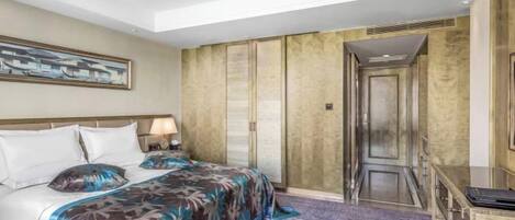 A hotel room with a large bed, a desk, and a chair. There is a painting on the wall and a door with a mirror.