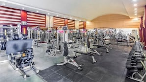 Ginásio com diversos equipamentos de exercício, incluindo máquinas de musculação e pesos livres.