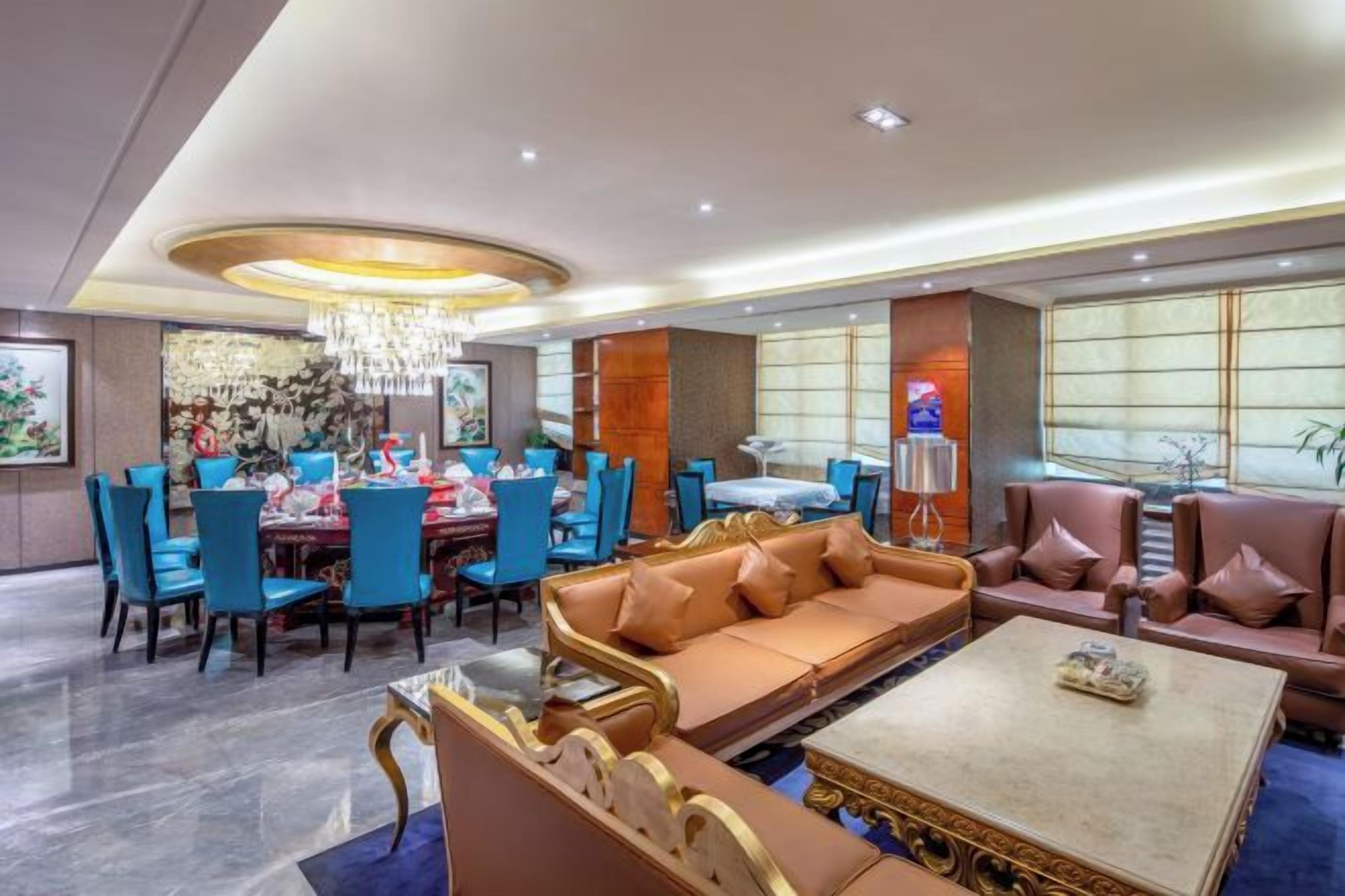 A hotel lobby with a dining area, sofas, and a chandelier.