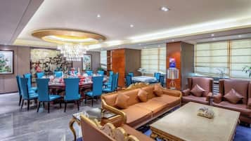 A hotel lobby with a dining area, sofas, and a chandelier.