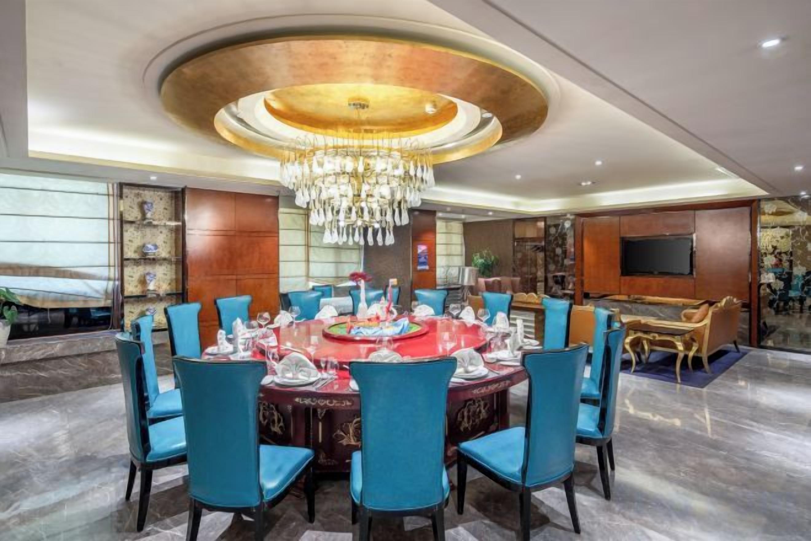 Un coin repas avec une table ronde, des chaises bleues et un lustre.