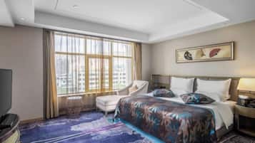 Habitación de hotel con una cama grande, una silla, un televisor y una ventana con cortinas.