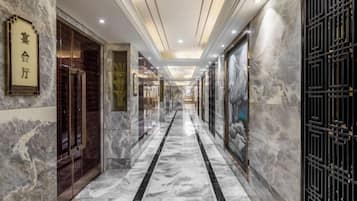 Un pasillo de hotel con suelo de mármol, una zona de recepción y una puerta con un letrero.