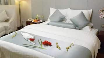A neatly made bed with pillows, a bedside table with a lamp, and a chair.