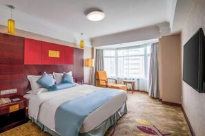 A hotel room with a large bed, a desk, a chair, a TV, and a window with curtains. - Enraton International Hotel (Xining)