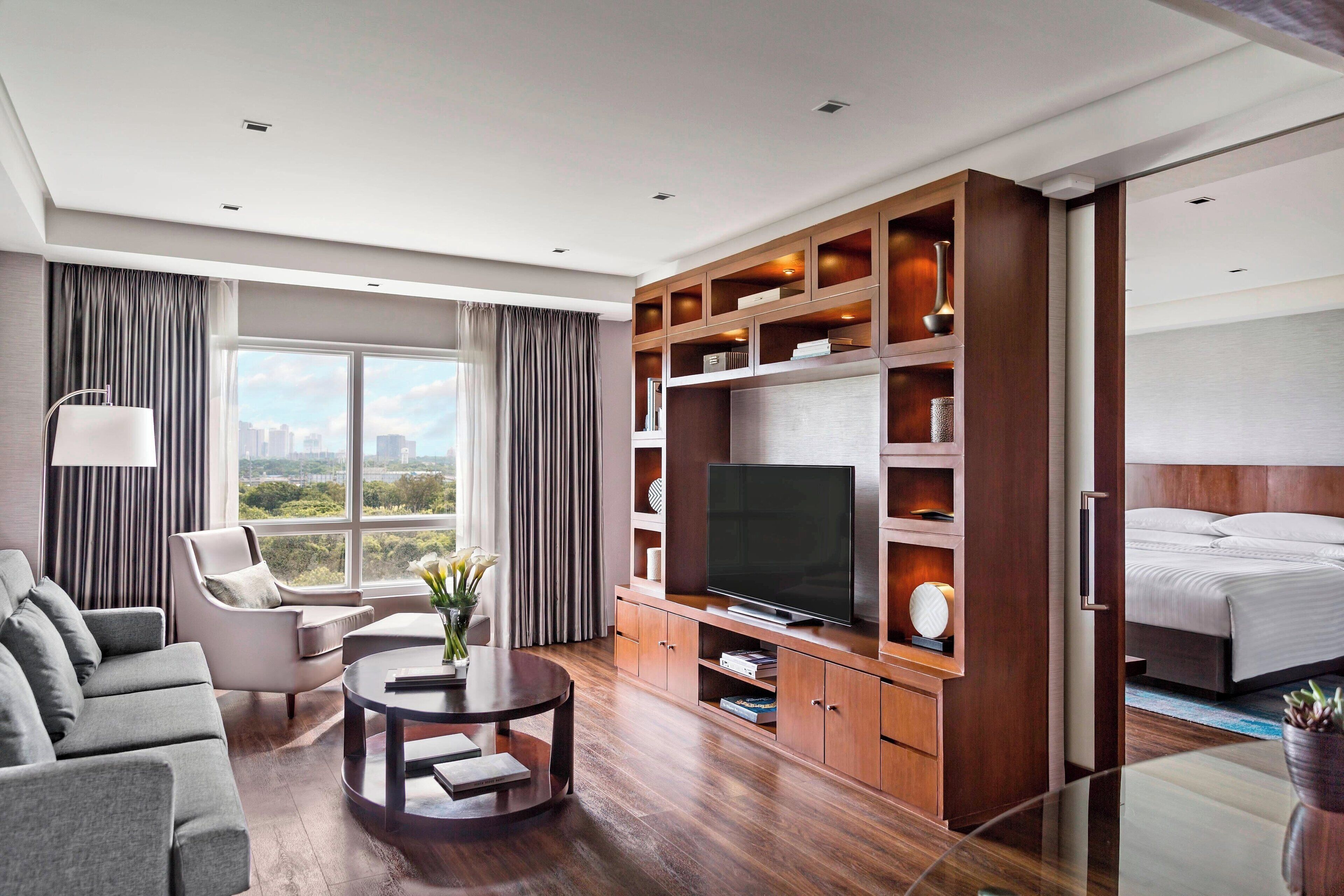 Una habitación de hotel moderna con un televisor de pantalla plana grande, un sofá, una mesa de comedor y una cama.