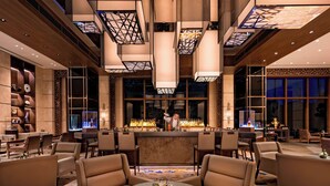 Eine moderne Bar mit hohen Decken, geometrischen Leuchten und einem Barkeeper.
