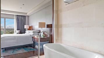 A modern hotel room with a large bed, a bathtub, and a city view.