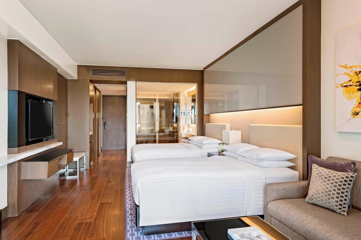 A hotel room with a large bed, a TV, a sofa, and a coffee table.
