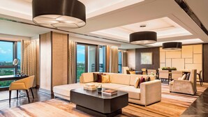 Ein modernes Wohnzimmer mit einer Couch, Sesseln, einem Couchtisch und einem Essbereich mit Stühlen und Tisch.