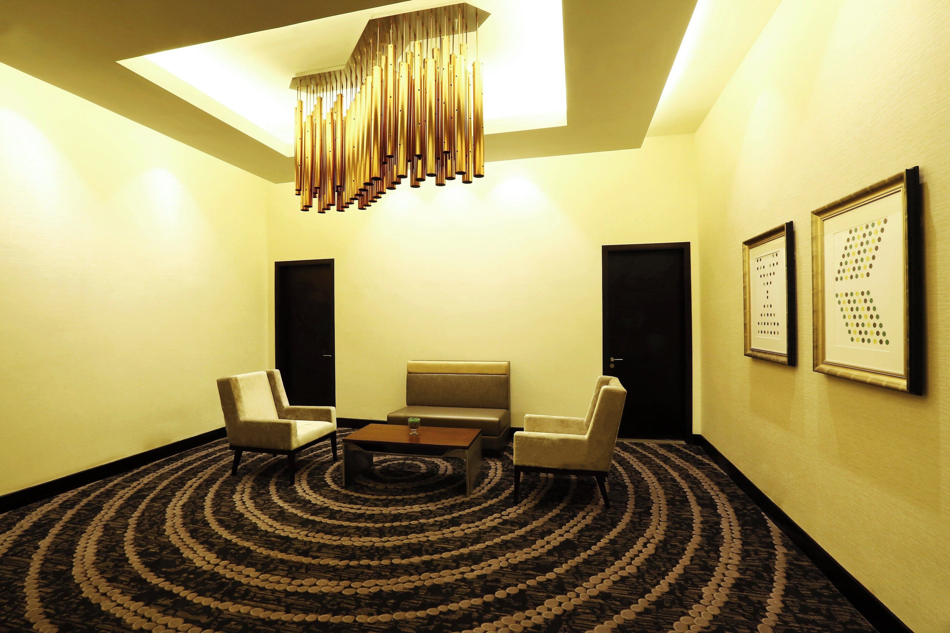 A conference room with a round table, two chairs, a sofa, and a patterned carpet.