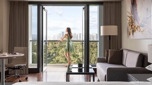 Ein Hotelzimmer mit großem Fenster, einem Bett, einem Sofa, einem Schreibtisch und einem Sessel.