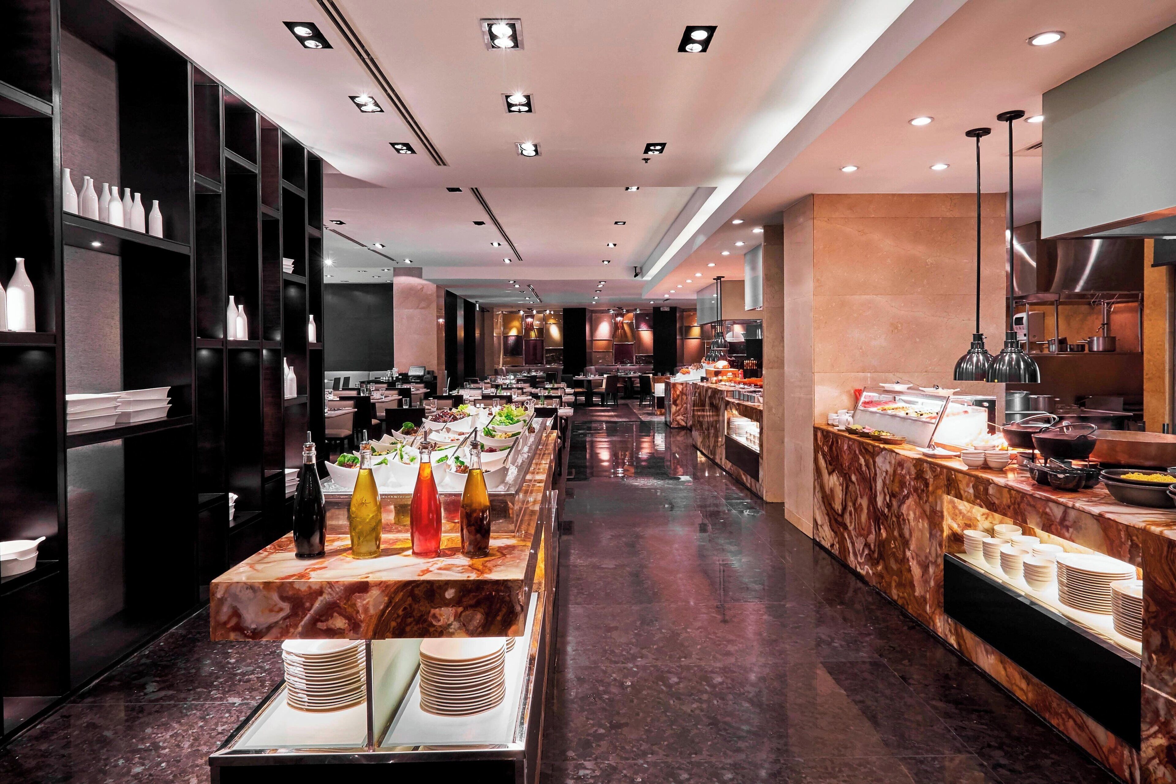 A modern hotel buffet with marble countertops, a variety of food options, and a clean, well-lit interior.