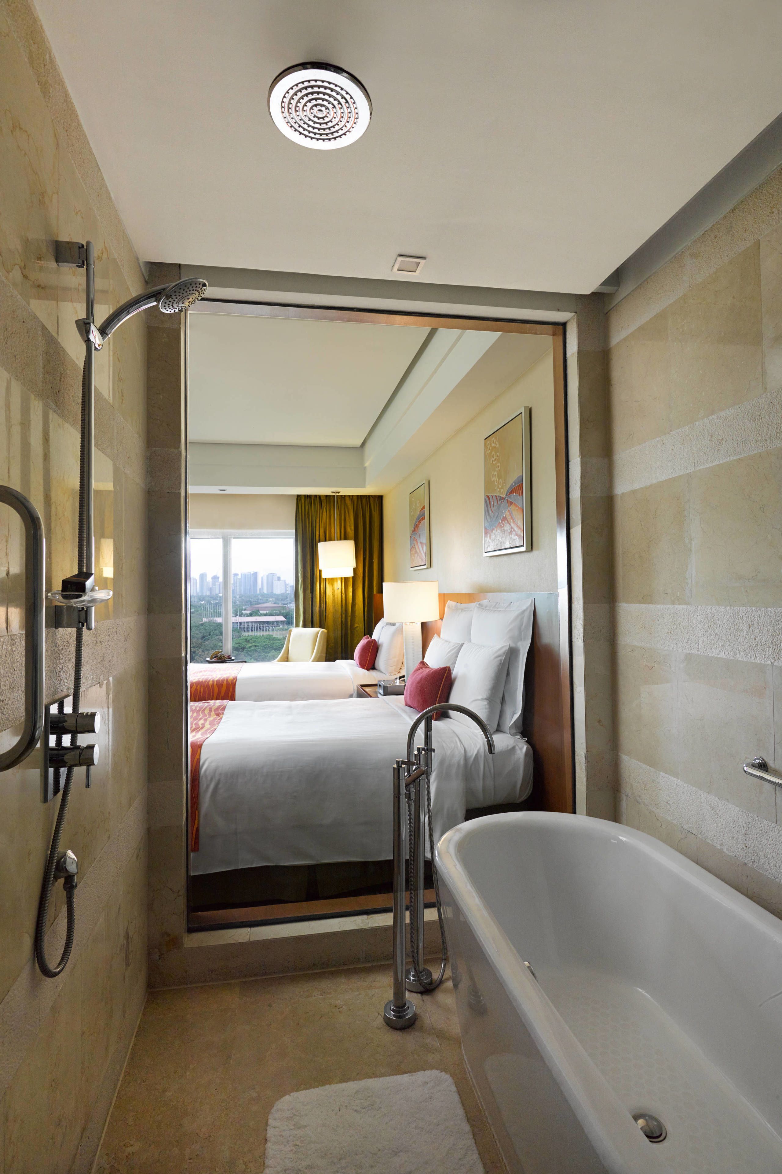 Une salle de bain moderne avec une baignoire, une douche et un lit donnant sur la ville.