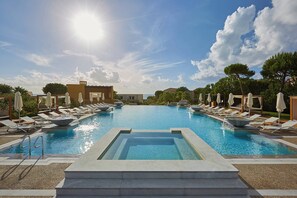 A swimming pool with lounge chairs and umbrellas, surrounded by buildings and trees. - The Westin Resort, Costa Navarino (Trifylia)