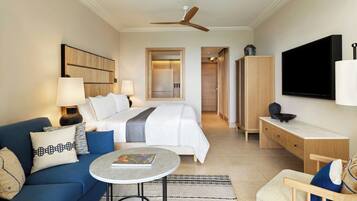 A hotel room with a bed, a sofa, a desk, a TV, and a ceiling fan.