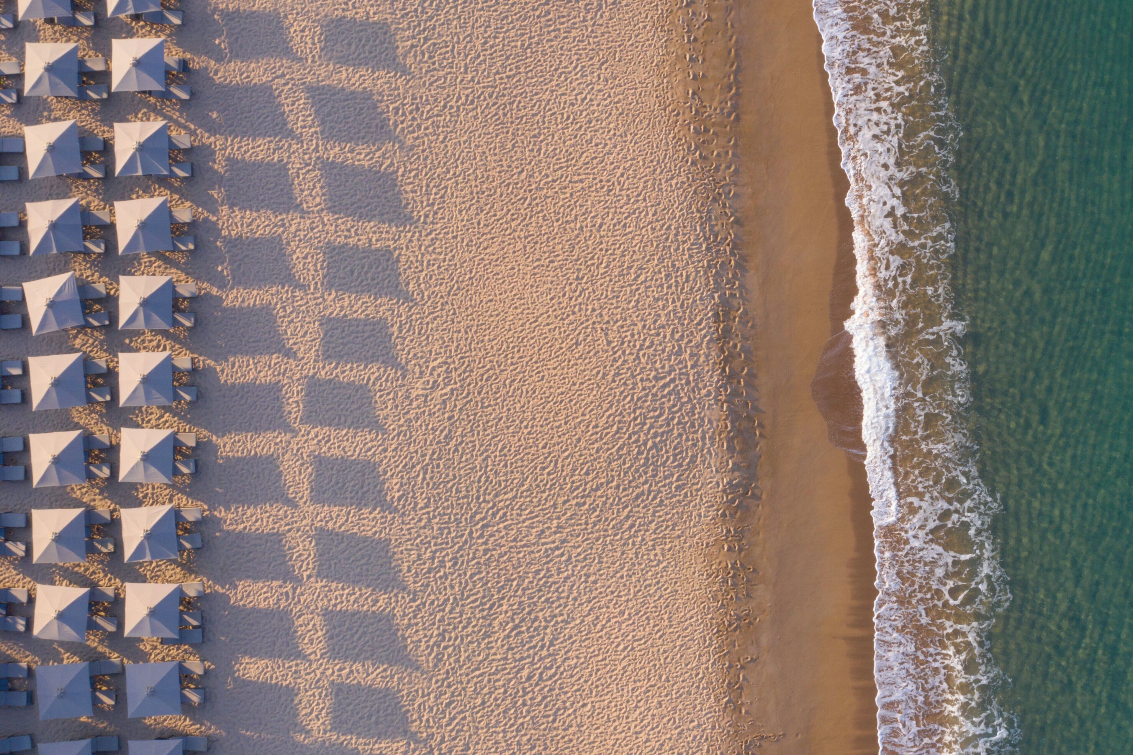 An aerial view of a beach with rows of umbrellas and sun loungers.