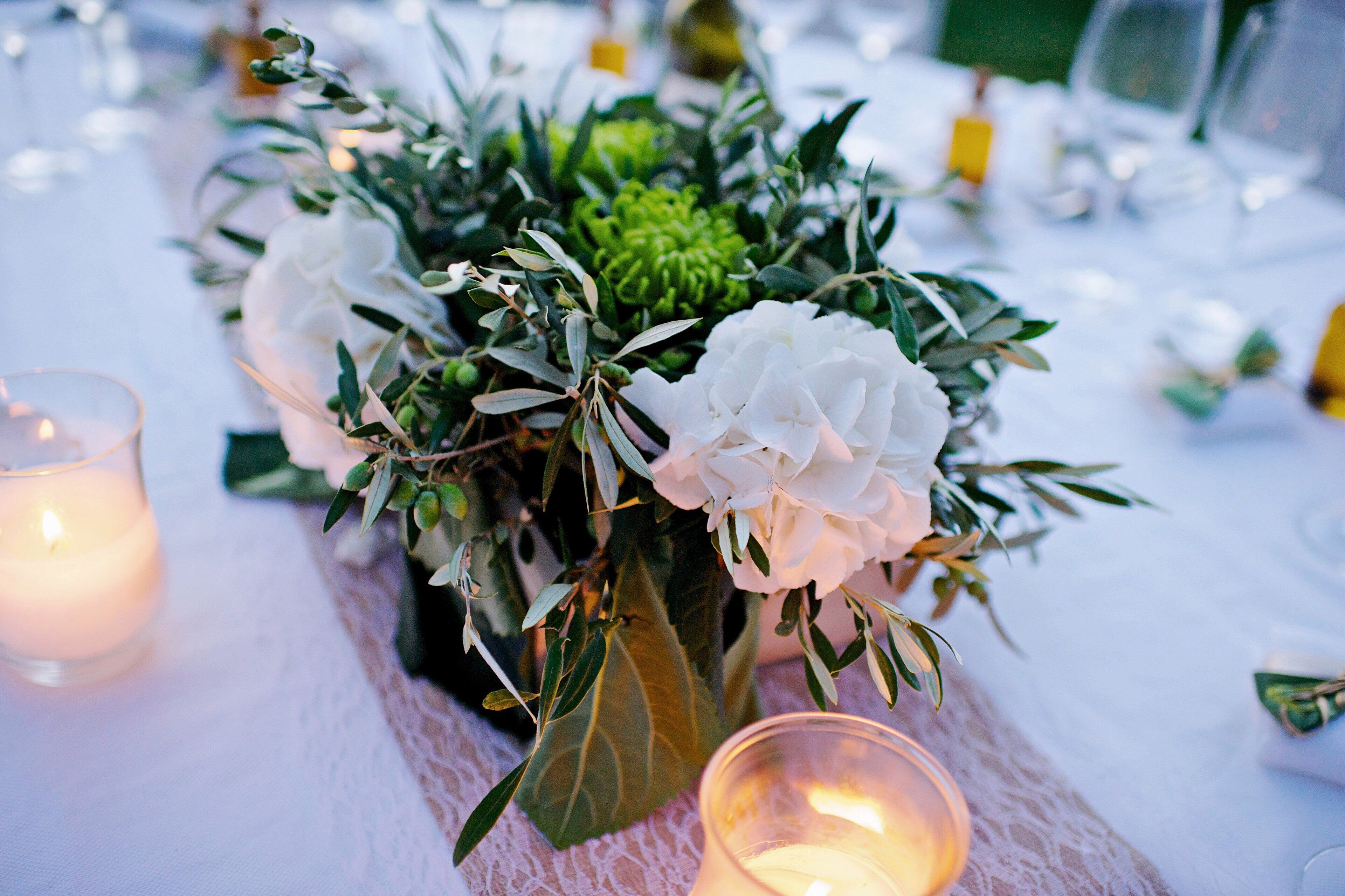 Una mesa dispuesta con un centro de flores, velas y un mantel de encaje.