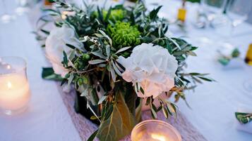 Una mesa dispuesta con un centro de flores, velas y un mantel de encaje.