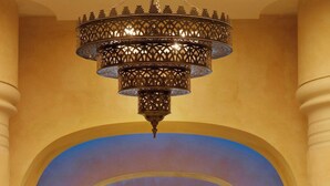 A grand hallway with a high ceiling, ornate chandeliers, and a series of columns. - The Westin Resort, Costa Navarino (Trifylia)