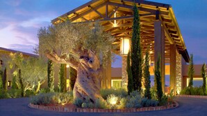 A modern building with a large tree sculpture in the foreground, surrounded by landscaped greenery. - The Westin Resort, Costa Navarino (Trifylia)