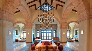 A spacious lobby with a central seating area, stone walls, and a chandelier. - The Westin Resort, Costa Navarino (Trifylia)