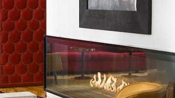 Een moderne woonkamer met een open haard, een rood structuurwand en een kunstwerk erboven.