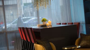 A modern dining area with a dark table, red chairs, and a small potted plant.