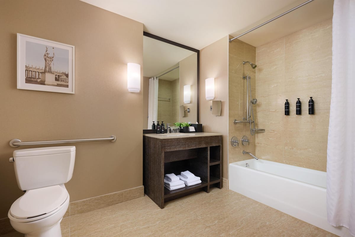Een moderne badkamer met toilet, wastafel, badkamermeubel en bad.