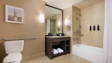 A modern bathroom with a toilet, sink, vanity, and bathtub.