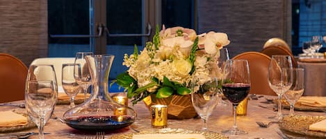 A table set for a meal with a vase of flowers, wine glasses, and plates.