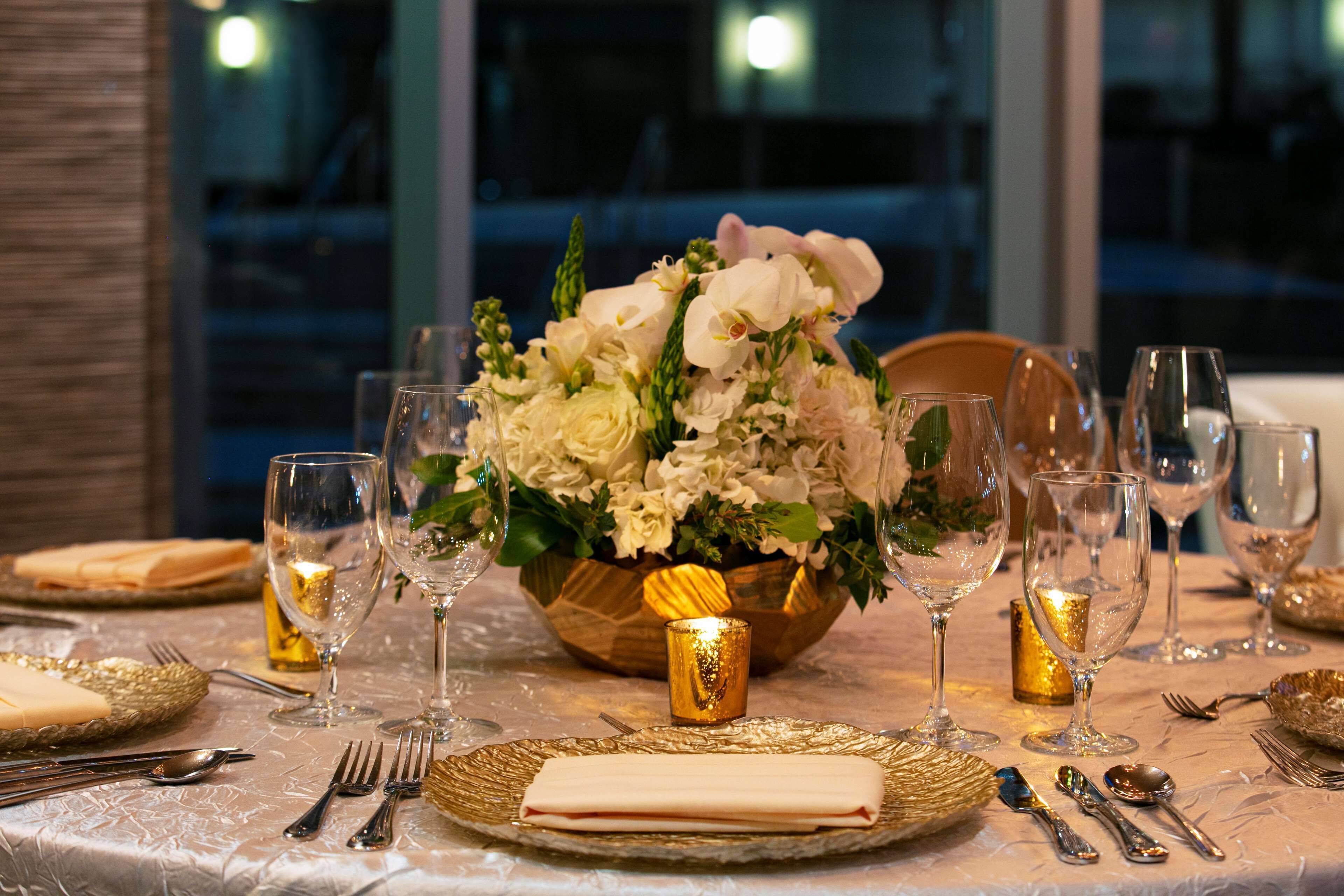 Una mesa dispuesta para una cena formal, con un centro de flores y velas.