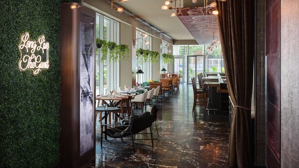 A modern restaurant interior with a green wall, hanging lights, and a long dining area. - The Royal Sonesta Chicago River North (Chicago)