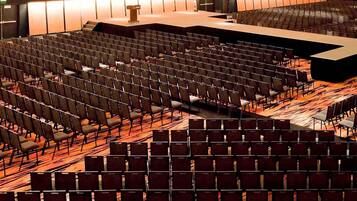 Une grande salle de conférence avec des rangées de chaises, une scène et un pupitre.