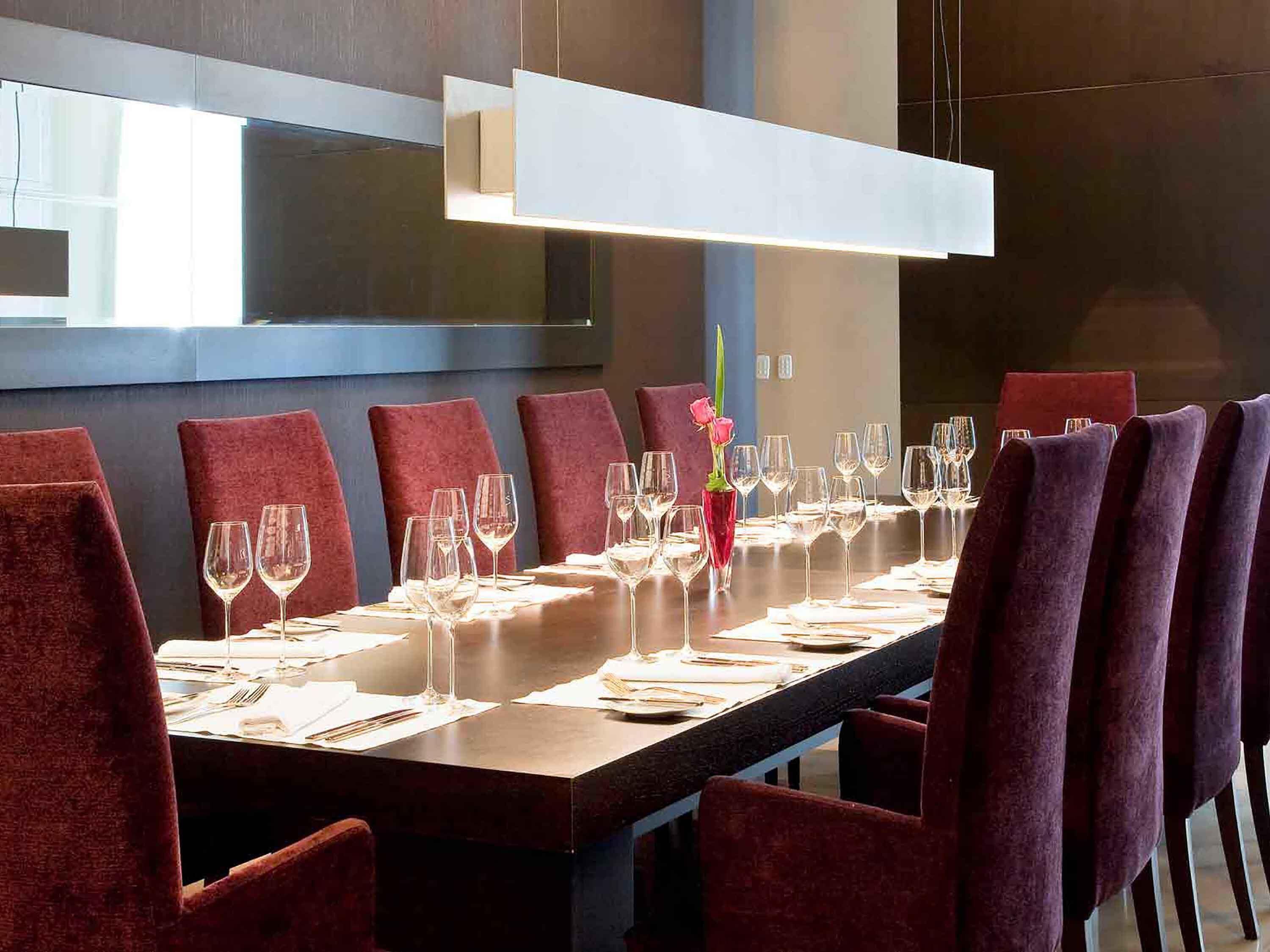 A conference room with a long table, red chairs, and a modern pendant light.