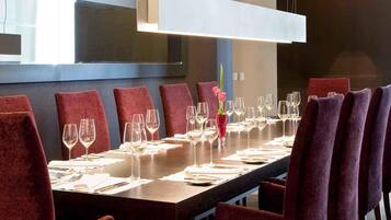 A conference room with a long table, red chairs, and a modern pendant light.
