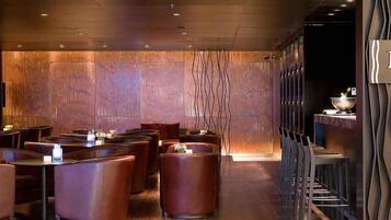 A restaurant interior with wooden panel walls, round tables, and chairs.