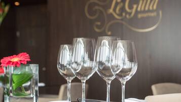 Una mesa dispuesta con copas de vino, un florero con una flor roja y una servilleta.