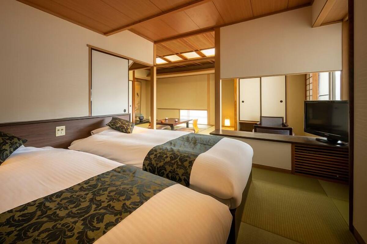 Une chambre d’hôtel avec deux lits, une télévision et un miroir.