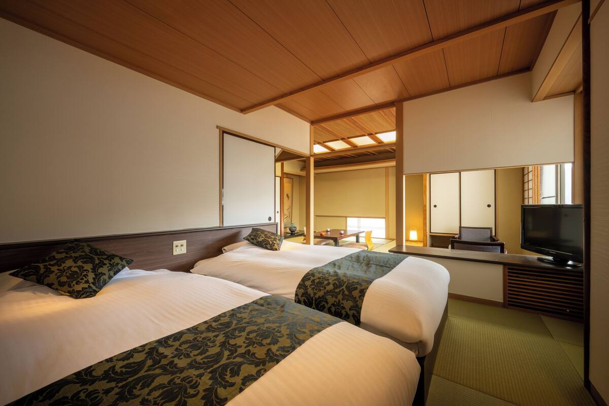 Une chambre d’hôtel avec deux lits, une télévision et un miroir.