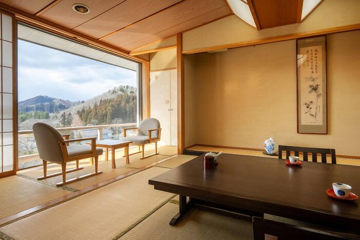 Une pièce de style japonais traditionnel, avec un sol recouvert de tatamis, une table basse et des chaises.