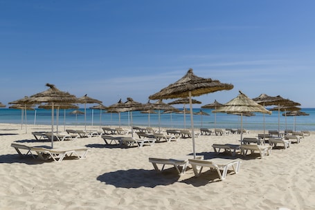 Playa privada, arena blanca, sillas reclinables de playa, sombrillas