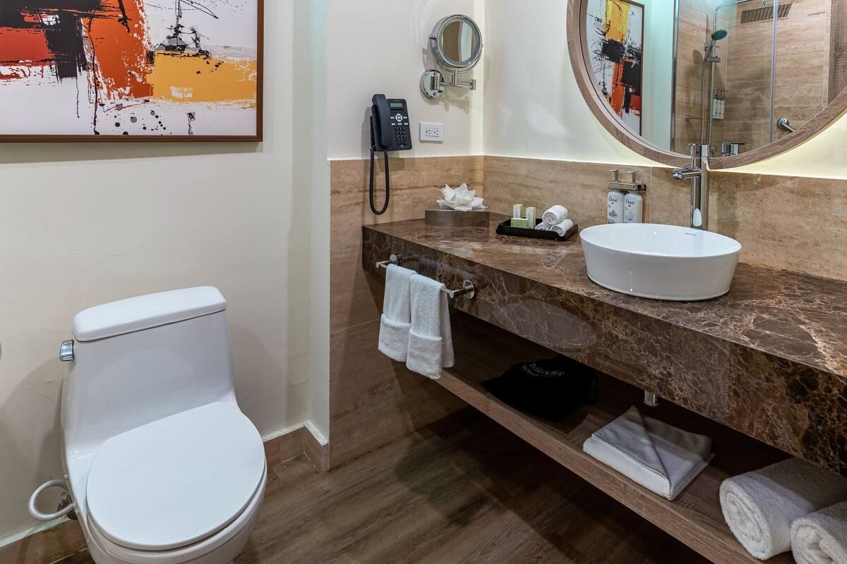 A modern bathroom with a white toilet, a marble countertop, a sink, and a mirror.