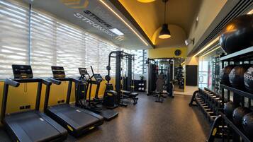 Un gimnasio con cintas de correr, máquinas de pesas y mancuernas.