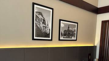 A hotel room with a bed, a nightstand, a lamp, and two framed pictures on the wall.