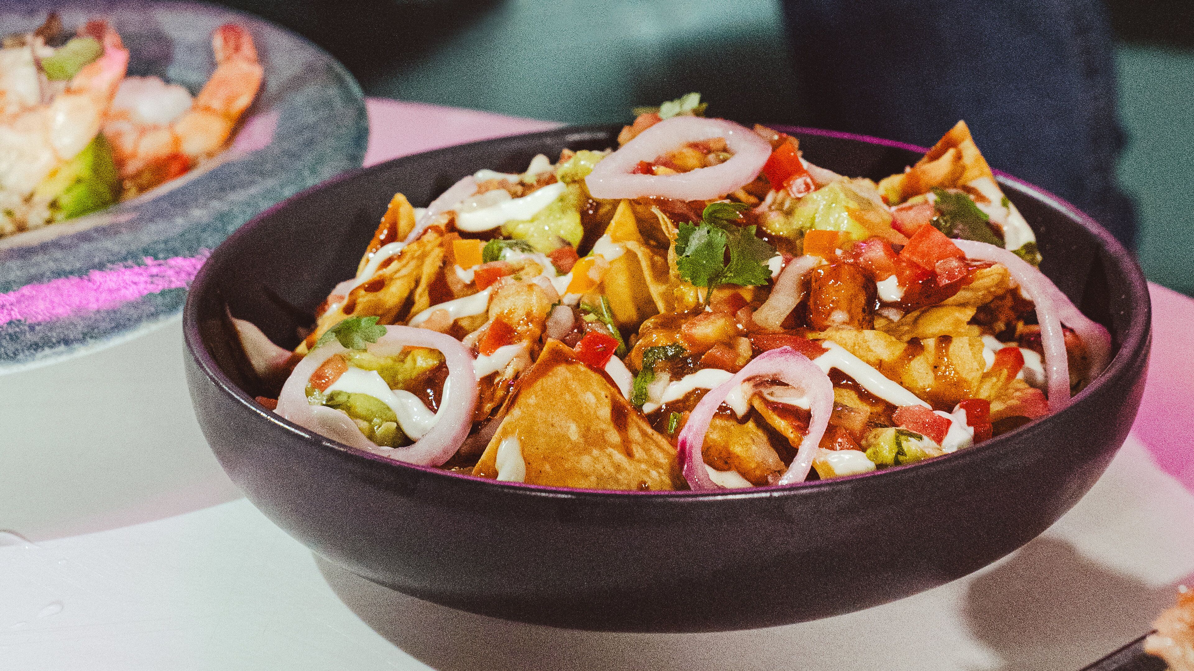 Un tazón de nachos cubiertos de queso, cebollas y jalapeños.