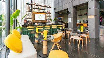 A modern hotel lobby with a bar area, seating arrangements, and a large window providing natural light.